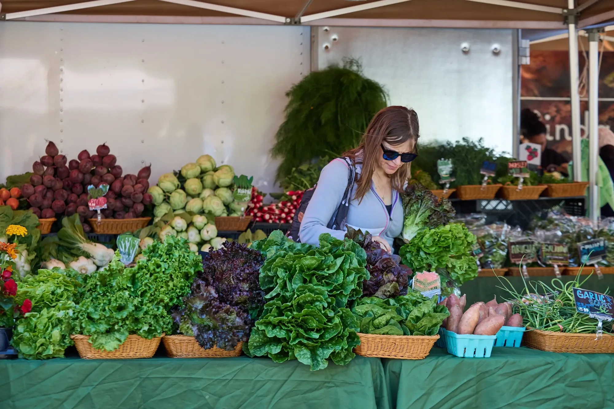 People walking through a booth at the farmers market