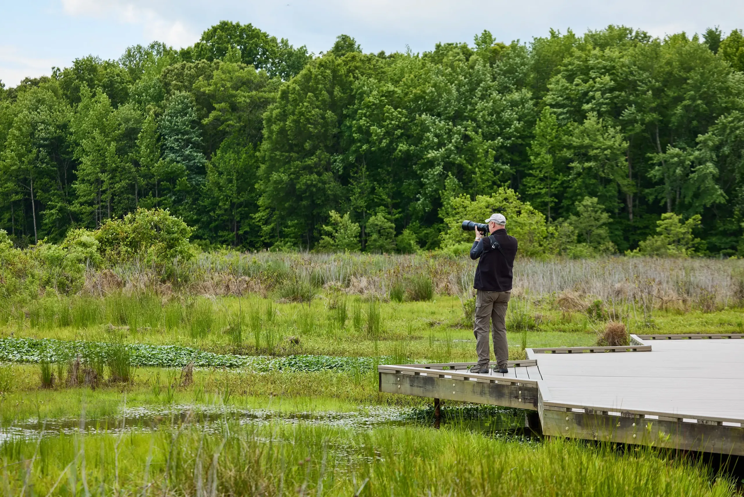 A man with a camera at the end of a boardwalk