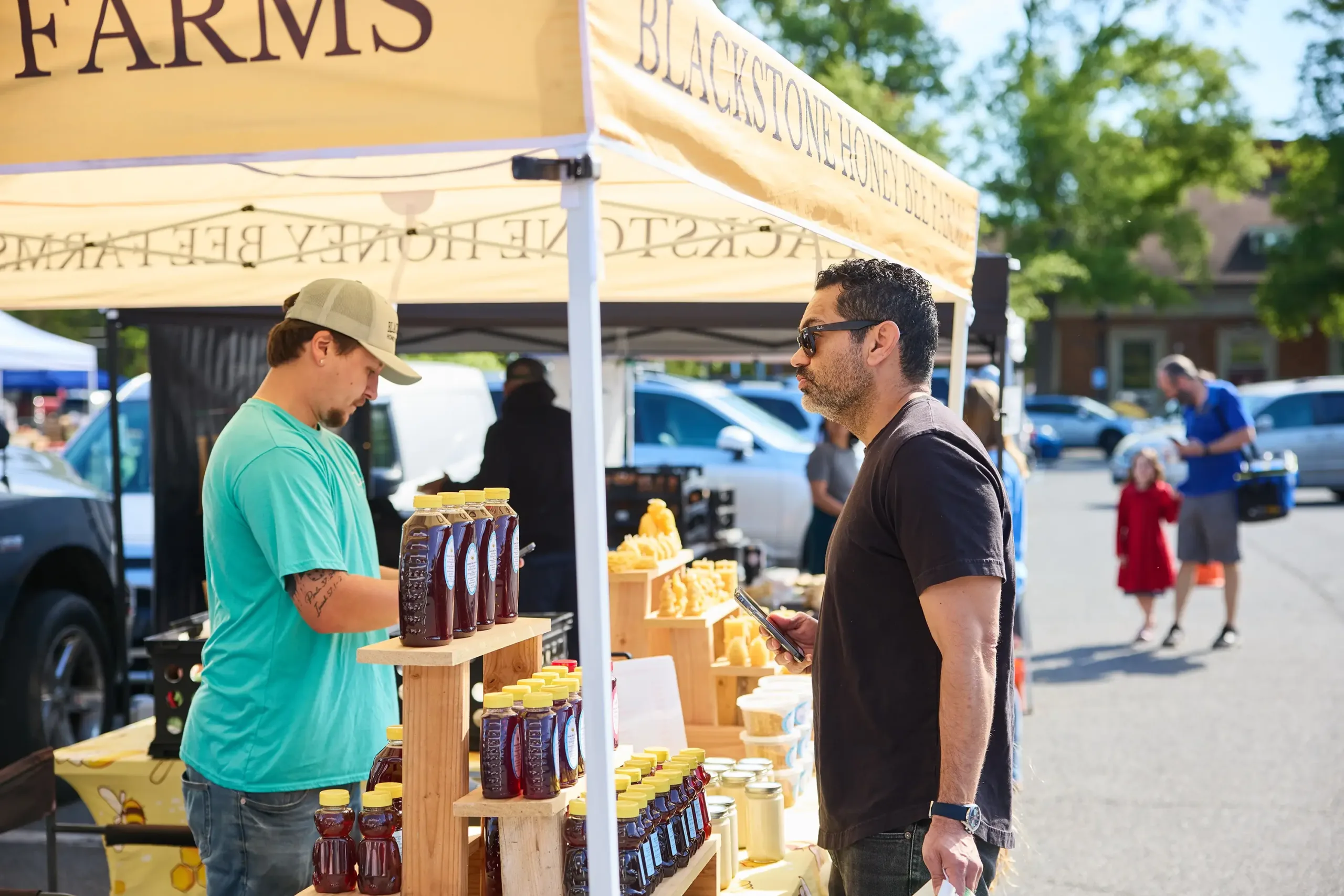 A man shopping a honey booth at the farmers market