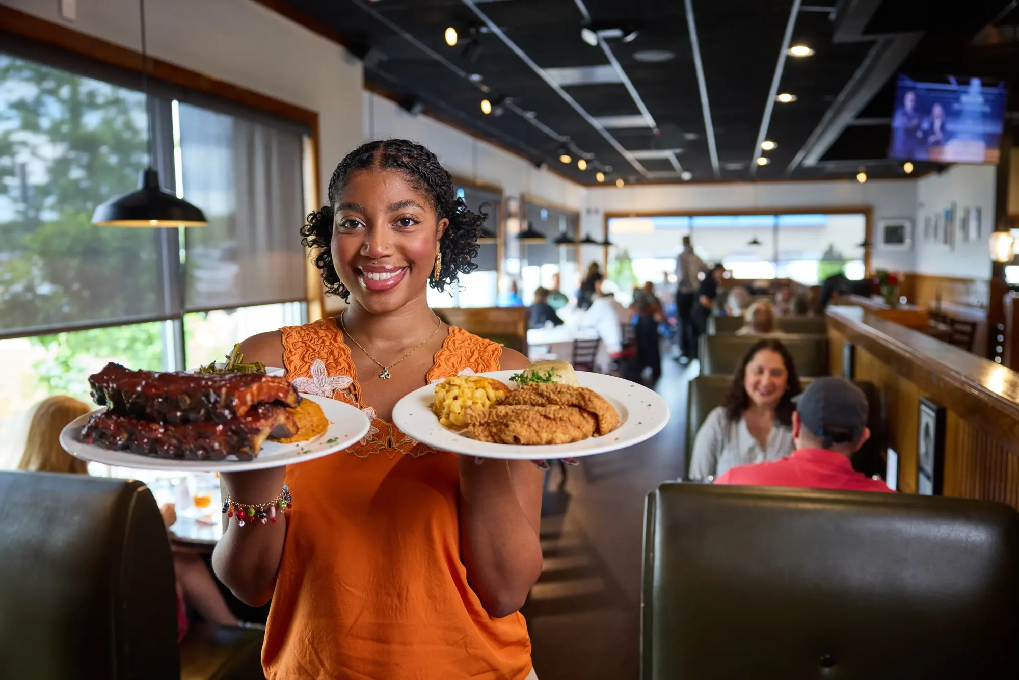 A woman holding plates of bbq and fried foods